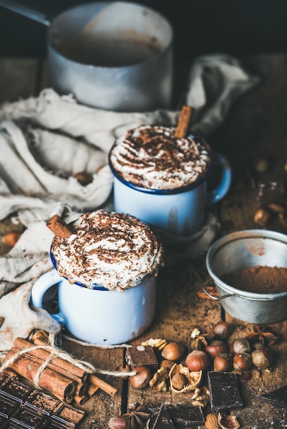 Hot chocolate with whipped cream cinnamon sticks and nuts