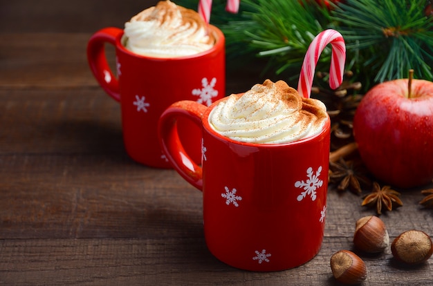 Hot chocolate with whipped cream in red cups. Christmas composition.