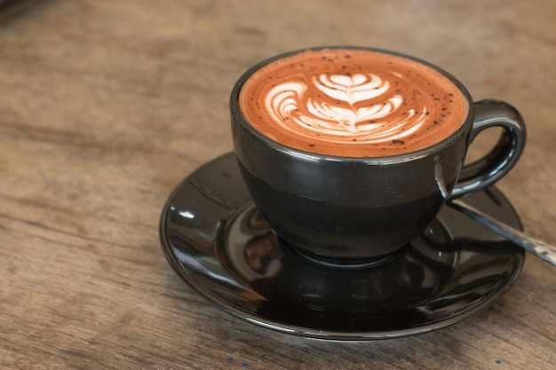 Hot chocolate with white cream heart on wooden desk