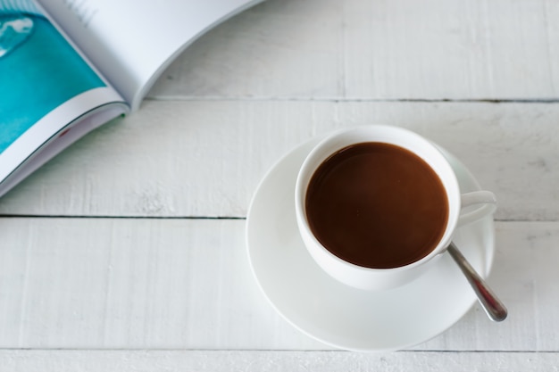 Foto cioccolata calda su legno bianco con libro aperto.