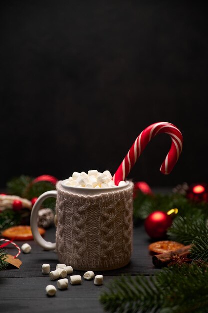 Hot cocoa drink with cinnamon stick and marshmallows with\
christmas decorations on background