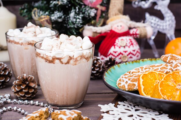 Hot cocoa with marshmallows and cinnamon in glasses on table with Christmas decorations