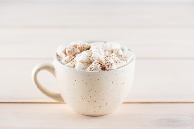 Hot cocoa with marshmallows in a white mug on a wooden table