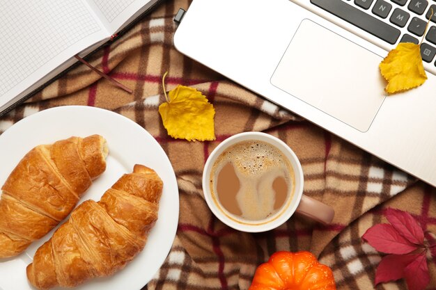 Hot coffee and autumn leaves with notebook on plaid - seasonal relax concept. Top view