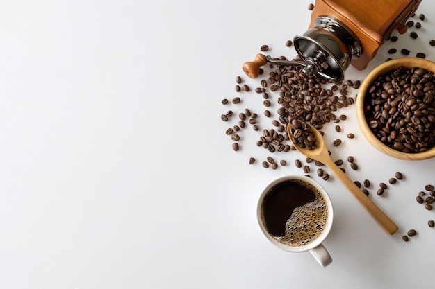 Hot coffee, bean and hand grinder on white table background. space for text. top view