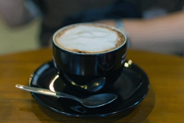 木製のテーブルの黒いカップのホットコーヒー