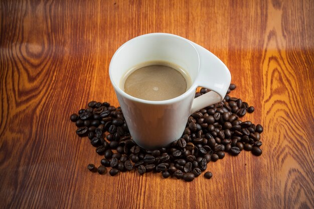 Hot coffee and coffee beans on wood background.