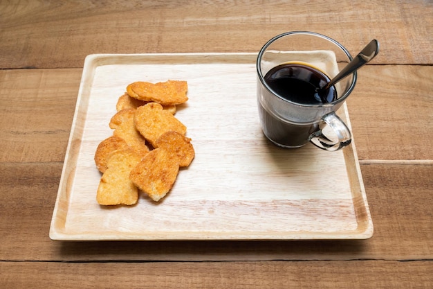 Tazza di caffè calda e colazione al forno su fondo di legno