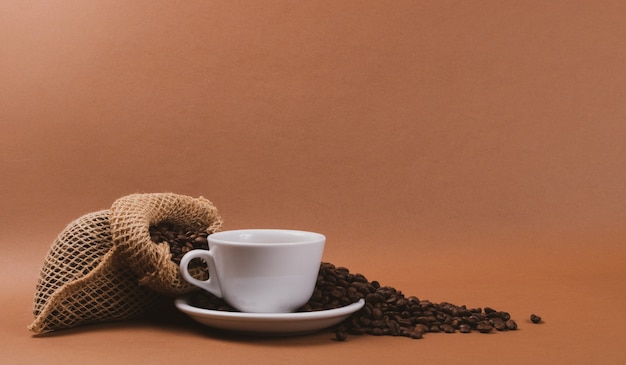 Чашка горячего кофе и кофейные зерна в мешковине