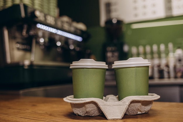 モダンなカフェ コーヒー ショップのカウンターで顧客を待っているホット コーヒー カップとデザートの紙袋