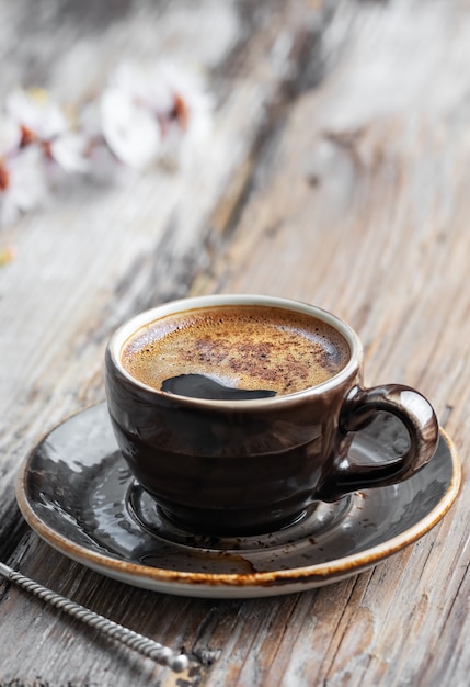 Hot coffee in a cup and flowering branches