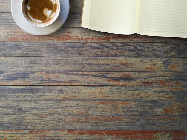 Hot coffee in cup and notebook on vintage wood table