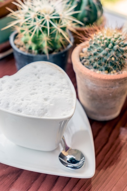 Hot coffee cup shape heart on table cactus