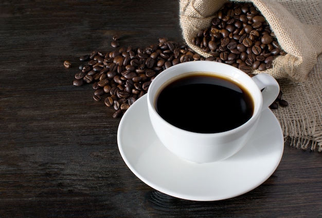 Tazza di caffè caldo con chicchi di caffè sul tavolo di legno