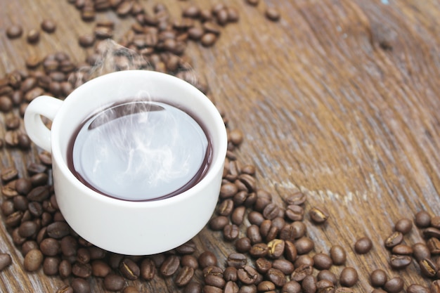 Hot coffee cup with seeds on wood