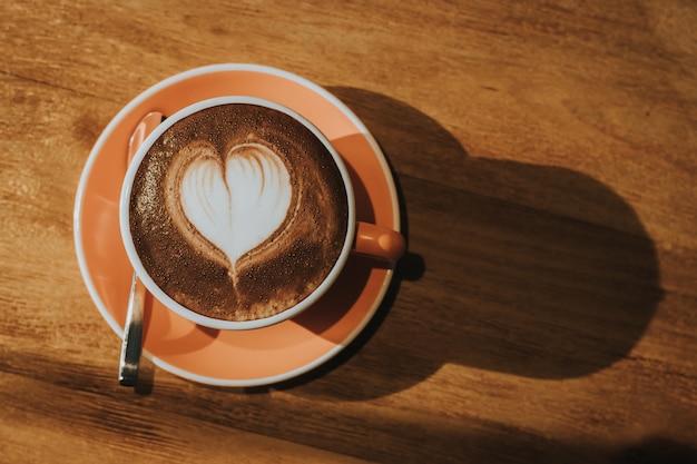 Photo hot coffee in cup on wood table soft focus, toned retro effect.