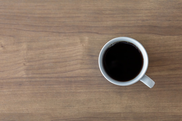 Hot coffee cup on wooden table background. top view