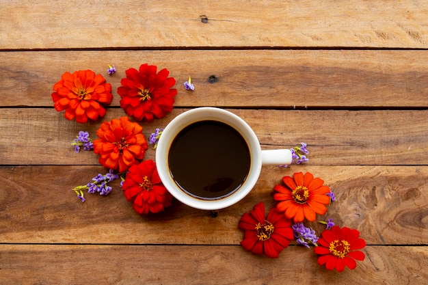 Foto caffè espresso caldo con fiori rossi zinnia elegans su legno