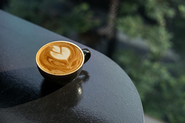 Hot coffee latte art heart shape on black table