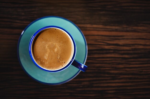 木製のテーブルにホットコーヒーカフェラテカップ。上面図