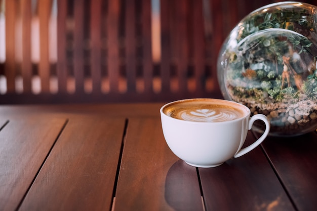 Hot coffee latte cup on wooden table with glass sphere