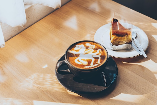 Hot coffee latte with latte art in the form of a horse milk foam in cup mug and Homemade chocolate cake on wood desk on top view As breakfast In a coffee shop at the cafeduring business work concept