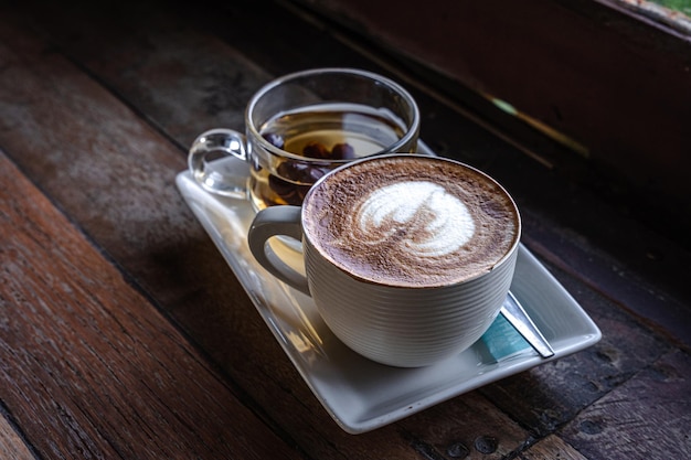 Hot coffee latte with latte art milk foam in cup mug hot tea on wood desk on top view As breakfast In a coffee Vintage style shop at the cafeduring business work concept