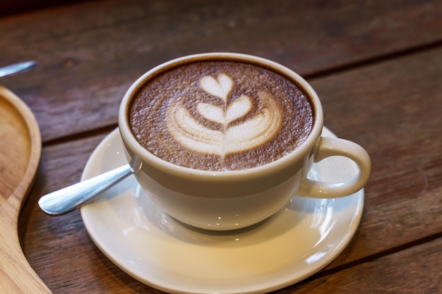 Фото Горячий кофе латте с молочной пеной латте-арт в кружке на деревянном столе сверху в качестве завтрака в кафе в кафе во время концепции бизнес-работы