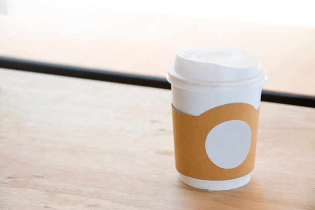 Hot coffee in paper cup isolated on wood table background. 