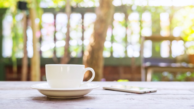 Hot coffee and smartphone on a wooden table.