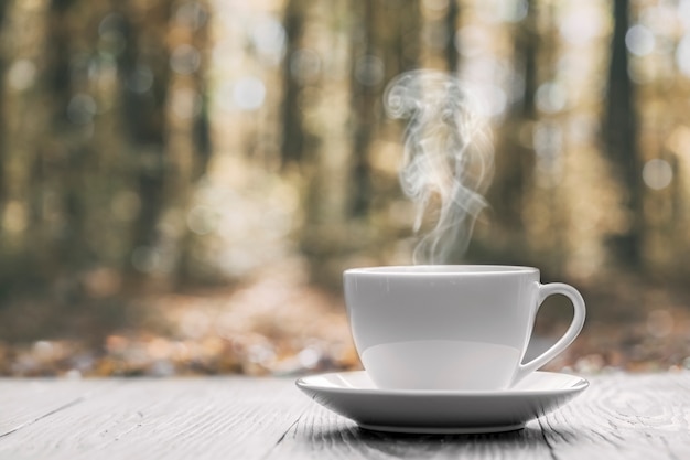 Hot coffee on the table on a autumn background