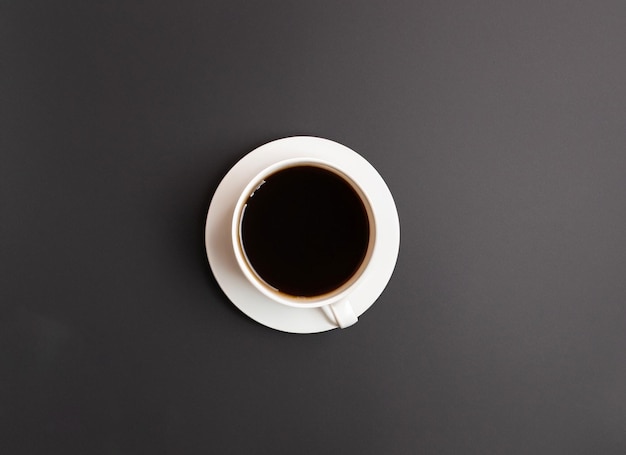 Hot coffee in a white coffee cup on dark background with copy space