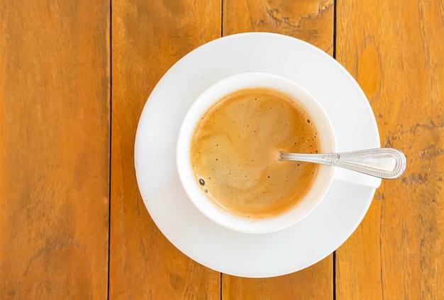 Caffè caldo in una tazza bianca con piattino su un tavolo di legno