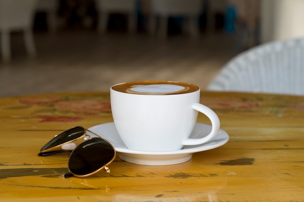 Foto caffè caldo con gli occhiali, che su un tavolo di legno