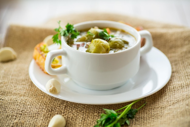 Горячий приготовленный суп с овощами брюссельской капусты и гренками в тарелке на деревянном столе