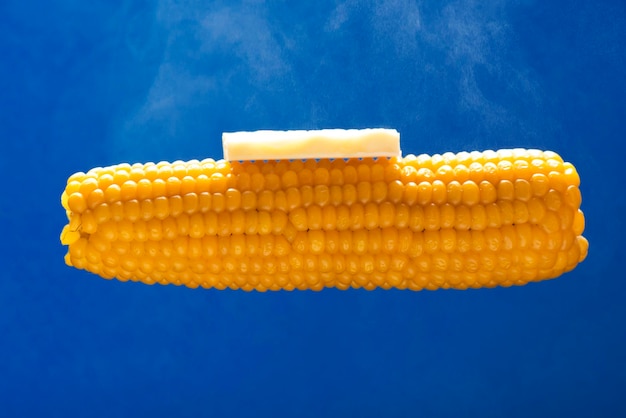 Горячая кукуруза с маслом и паром на синем фоне