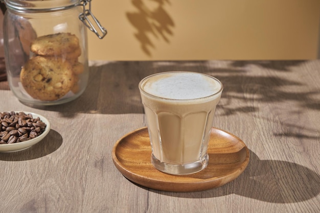 Hot creamy milk in coffee is served with cookies hot latte coffee drink in glass with cream milk on wooden table breakfast beverage morning concept