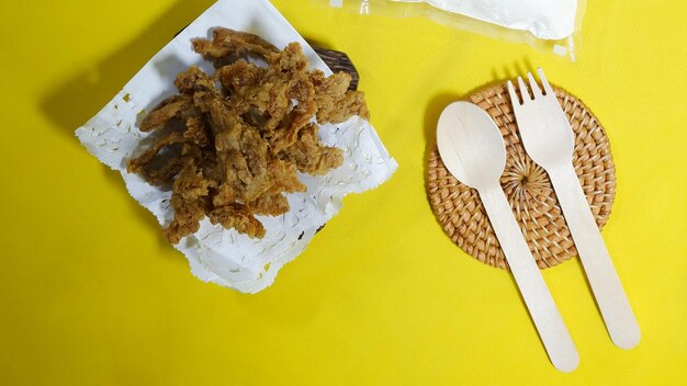 Hot Crispy Fried Intestines or usus goreng Food on a plate with wooden spoon and fork