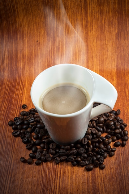 Tazza di caffè calda e fagioli con fumo.