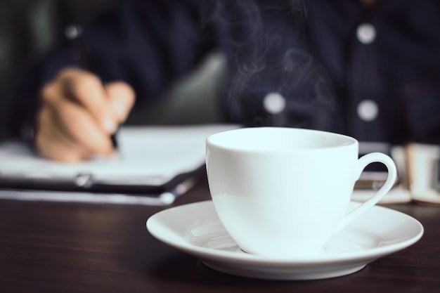 hot cup of coffee and businessman working background