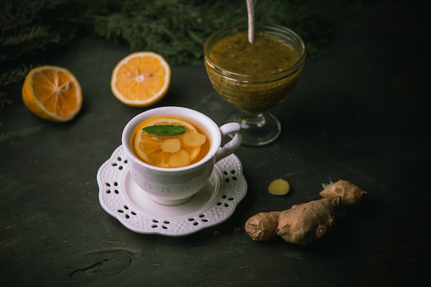 Photo hot cup of green tea with lemon,ginger,confiture on black surface,top view