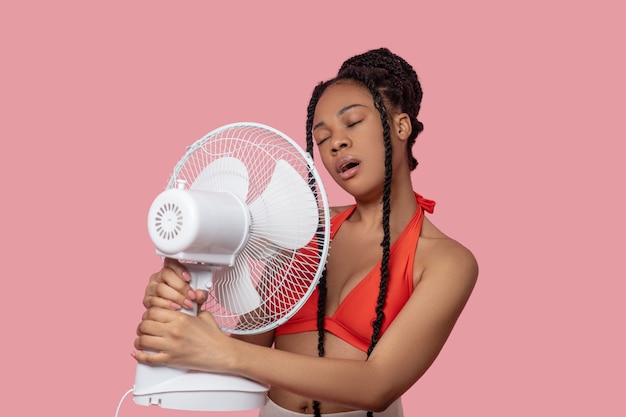 Hot days. Smiling african american woman holding a fan looking tired from heat