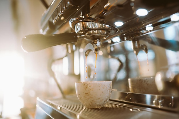 뜨거운 맛있는 커피가 커피 머신에서 커피 컵으로 어지고 있습니다.