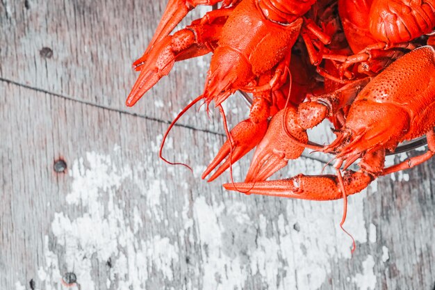 Hot delicious crayfish with a plate on rustic background. Delicious red boiled crayfishes on table, closeup. Banner design