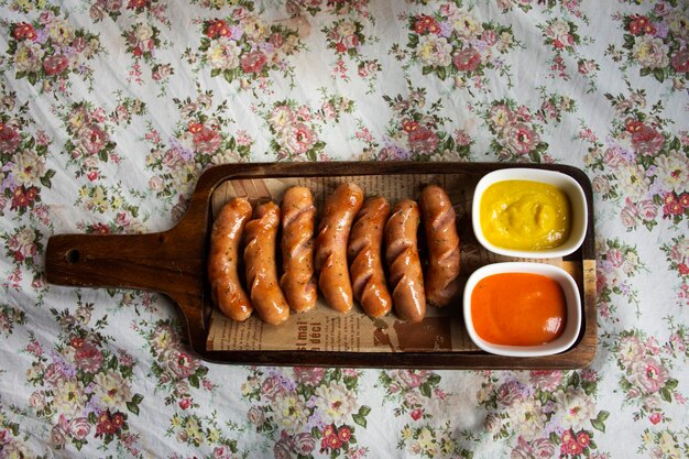 Немецкая колбаса хот-дог и кетчуп с приправами подаются на деревянном подносе для путешественников, тайские люди отдыхают, отдыхают, едят и пьют в кафе-ресторане в Бангкоке, Таиланд