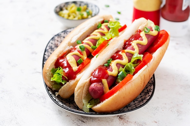 Hot dog with grilled sausage tomato and lettuce on light background American hot dog