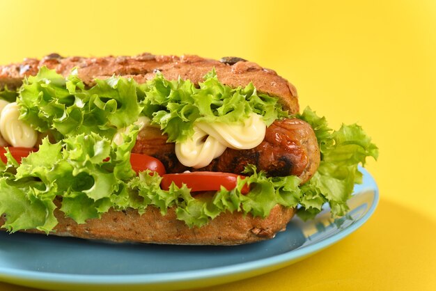 Hot dog with lots green salad and fried sausages