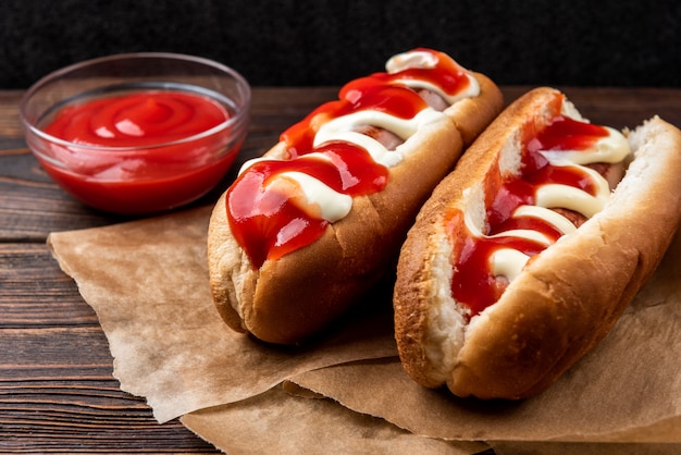 Hot dog with mayonnaise and ketchup on dark wooden 