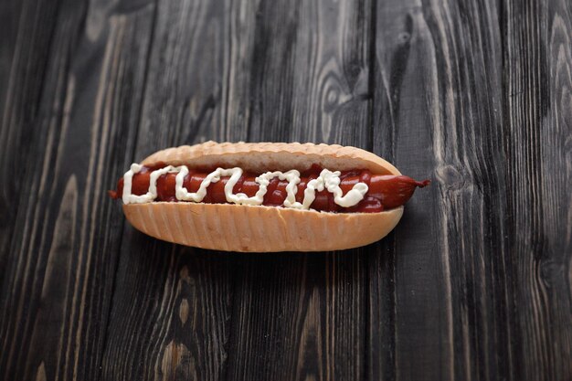 Hot dog with smoked sausage and mayonnaise on wooden background