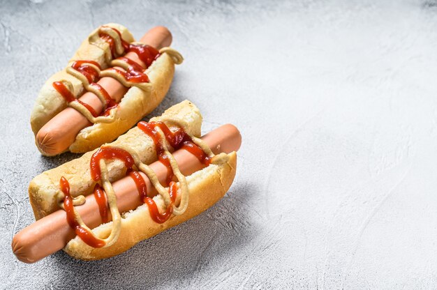 Hot Dog with Yellow Mustard and red ketchup. White background. Top view. Copy space.